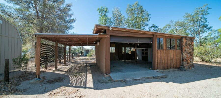 a building with a covered entrance in the middle of a dirt field