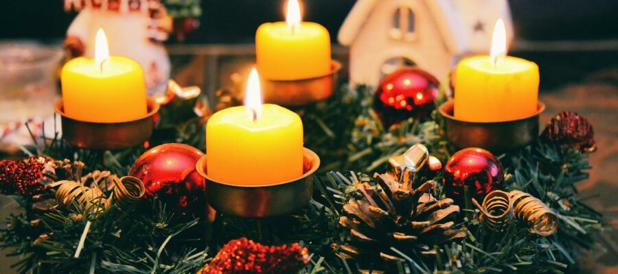 Cozy Christmas display featuring candles, ornaments, and festive wreath in warm candlelight.