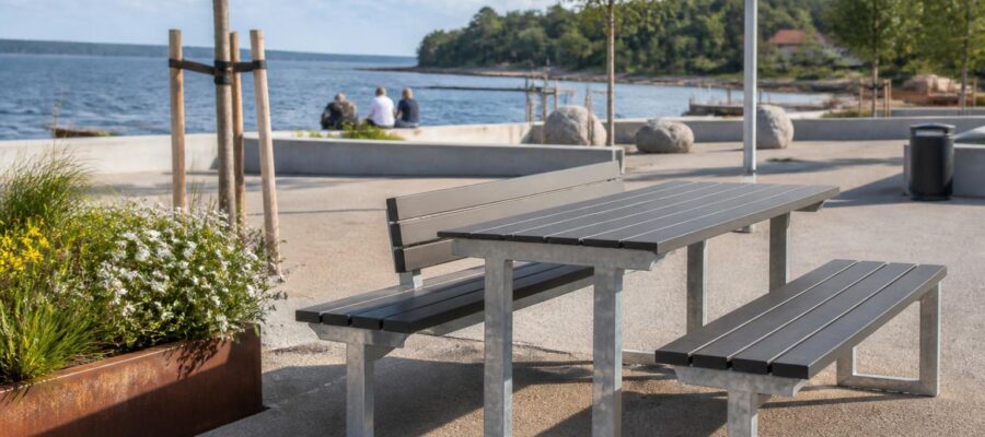 Tischsitzbank outdoor im skandinavischen Design als Lösung für öffentliche Außenbereiche Eine Tischsitzbank im skandinavischen Stil vereint klare Linien, Funktionalität und eine schlichte Ästhetik in Außenbereichen wie Parks, Schulhöfen oder Rastplätzen. Diese Kombination aus Sitzfläche und Tisch bildet ein kompaktes Möbelstück, das für Stabilität und Struktur sorgt. Gerade im öffentlichen Raum ist es entscheidend, dass solche Sitzgruppen langlebig, pflegeleicht und vielseitig einsetzbar sind. Der Einsatz von beständigen Materialien wie feuerverzinktem Stahl und recyceltem Kunststoff gewährleistet auch bei intensiver Nutzung eine verlässliche Funktion. Die Materialwahl zahlt sich zudem im Betrieb aus: Planken aus recyceltem Kunststoff kommen ohne Anstrich aus, und feuerverzinkter Stahl ist dauerhaft vor Korrosion geschützt. Eine harmonische Integration des Möbels in die Umgebung trägt dazu bei, das Gesamtbild eines Platzes aufzuwerten. Im Folgenden wird aufgezeigt, worauf bei einer modernen Tischsitzbank zu achten ist und wie sich praktische Lösungen gestalten lassen. Auch Aspekte wie Farbwahl und flexible Befestigung spielen bei der Auswahl eine Rolle, um unterschiedlichen Anforderungen gerecht zu werden. Warum eine Tischsitzbank im Außenbereich sinnvoll ist Mit einer Tischsitzbank entsteht ein fester Treffpunkt für Gruppen in Parks oder auf Schulhöfen. Die Kombination aus Sitz- und Ablagefläche definiert einen Ort zum Essen, Spielen oder Arbeiten im Freien. Dies trägt dazu bei, die Aufenthaltsqualität zu erhöhen und Begegnungen zwischen Menschen zu ermöglichen. Solche Plätze fördern die Kommunikation und laden dazu ein, gemeinsam Zeit im Freien zu verbringen. Besonders Eltern, Lehrende oder Betreuende wissen die Vorteile zu schätzen, da Kinder sicher und bequem zusammen kommen können. Eine Tischsitzbank unterstützt somit auch ein soziales Miteinander beim gemeinsamen Lernen, Basteln oder Picknicken. Im öffentlichen Raum gelten hohe Anforderungen an Haltbarkeit und Widerstandsfähigkeit. Eine moderne Bank-Tisch-Kombination zeichnet sich durch robuste Materialien aus, die wenig Pflege erfordern und langfristig nutzbar sind. Durch ihre stabile Bauweise bietet sie Schutz vor Vandalismus und lässt sich gut in verschiedene Flächen integrieren. Auch die schnelle Reinigung und einfache Wartung sind wichtig, damit der Platz jederzeit nutzbar bleibt. Worauf bei Qualität und Auswahl geachtet werden sollte Bei der Auswahl empfiehlt es sich, auf eine solide Konstruktion aus wetterfesten Materialien wie feuerverzinktem Stahl sowie Planken aus recyceltem Kunststoff zu setzen. Diese Werkstoffe schützen zuverlässig vor Feuchtigkeit, Sonneneinstrahlung und Frost, sodass die Sitzgruppe über lange Zeit ansprechend bleibt. Ergonomische Maße spielen ebenfalls eine wichtige Rolle: Angemessene Sitzhöhen, ausreichend breite Flächen sowie gegebenenfalls Rückenlehnen sorgen für Komfort. Darüber hinaus sollte geprüft werden, ob das Modell leicht zu montieren ist oder spezielle Befestigungsmöglichkeiten bietet, um Diebstahl und Umkippen vorzubeugen. Rutschfeste Füße und abgerundete Kanten erhöhen die Sicherheit und minimieren das Verletzungsrisiko, insbesondere an stark frequentierten Orten. Für bestimmte Einsatzbereiche gibt es auch barrierefreie Varianten mit verlängerter Tischplatte, die Rollstuhlfahrern eine einfache Nutzung ermöglichen. Weitere Informationen und unterschiedliche Modelle finden sich unter Bank Tisch Kombination. Auch die Auswahl verschiedener Farbvarianten unterstützt eine individuelle Gestaltung passend zur Umgebung. Einsatzmöglichkeiten im Alltag Tischsitzbänke kommen vorzugsweise dort zum Einsatz, wo viele Menschen aufeinandertreffen – etwa in Parks, an Spielplätzen oder auf Schulhöfen. Auch in Pausenbereichen von Unternehmen oder an Rastplätzen entlang von Wegen leisten sie gute Dienste. Bei Veranstaltungen bieten sie zudem einen festen Platz zum Verweilen. Die vielseitigen Sitzgruppen können fest installiert oder flexibel aufgestellt werden, um unterschiedlich großen Gruppen gerecht zu werden. Insbesondere in Bildungseinrichtungen sind sie wertvoll, da sie als Arbeitsstation im Außenbereich dienen können. Auch bei Festen und öffentlichen Feiern bieten diese Möbel praktische Ablagen für Speisen und Getränke. Dank ihrer stabilen Ausführung trotzen diese Bänke nicht nur den Witterungsbedingungen, sondern halten auch einer intensiven Nutzung durch verschiedene Besuchergruppen stand. Das klare skandinavische Design fügt sich in unterschiedlichste Umgebungen ein – sowohl in städtischen als auch naturnahen Bereichen. Mit einer passenden Bank-Tisch-Kombination lässt sich die Aufenthaltsqualität im Außenraum gezielt steigern. So werden Außenflächen nicht nur attraktiver, sondern auch über viele Jahre nutzbar gemacht.
